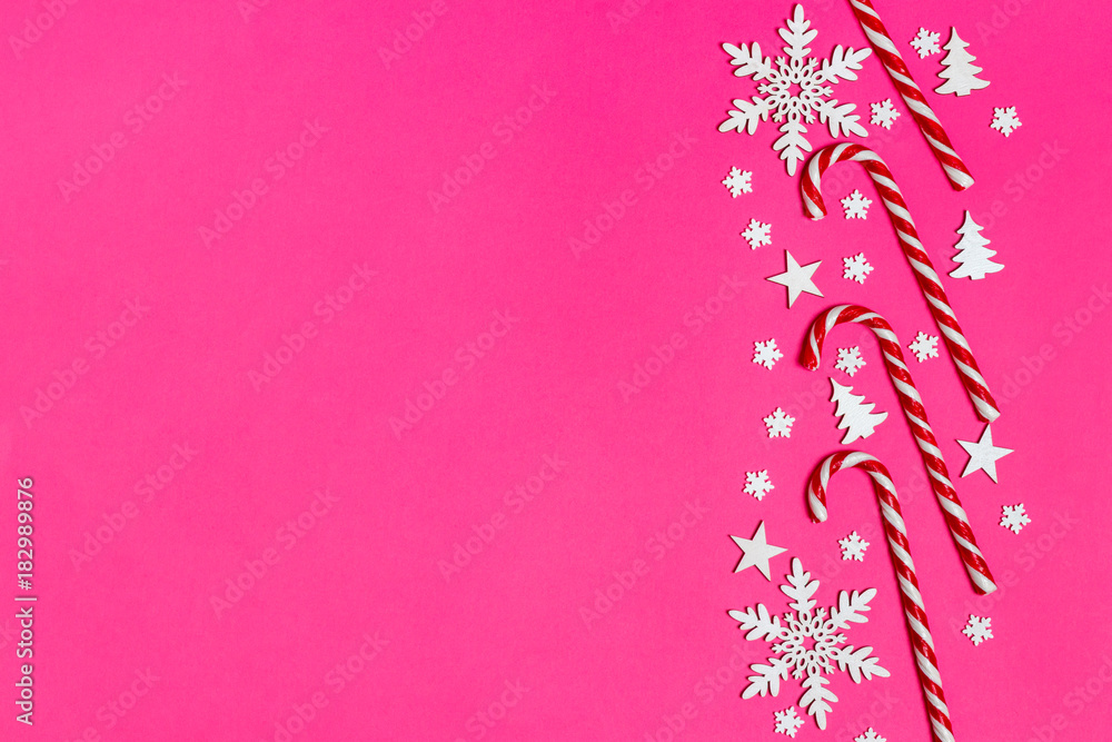 Christmas candy cane lied evenly in row on pink background with decorative snowflake and star. Flat lay and top view Christmas candy cane lied evenly in row on pink background with decorative snowflake and star. Flat lay and top view
