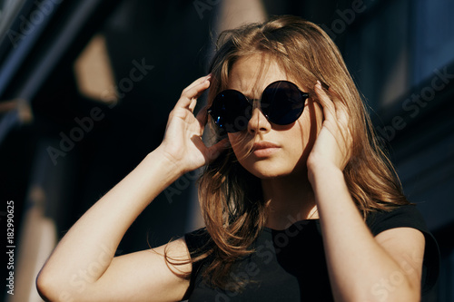 Young beautiful woman with long hair in sunglasses outside in the city