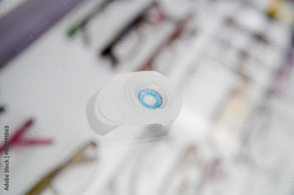 Close up of a blue contact lenses, inside the optical over a showcase in a blurred background