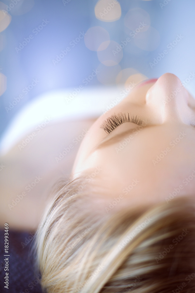 Fototapeta premium Young woman lying on a massage table,relaxing with eyes closed. Woman. Spa salon
