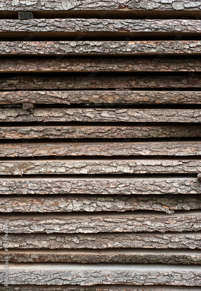 Folded wooden brown and gray planks in a sawmill. Piled alder boards as texture for design. Folded wooden brown and gray planks in a sawmill. Piled alder boards as texture for design.