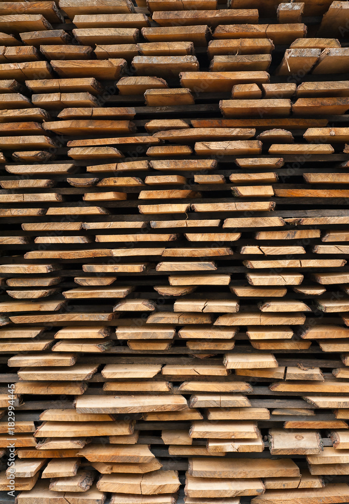 Folded wooden brown and gray planks in a sawmill. Piled alder boards as texture for design. Folded wooden brown and gray planks in a sawmill. Piled alder boards as texture for design.