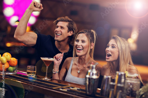 Fotografie Group Of Friends Enjoying Drink in Bar