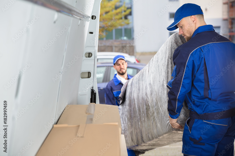 Two Movers Unloading Furniture From Truck Two Movers Unloading Furniture From Truck