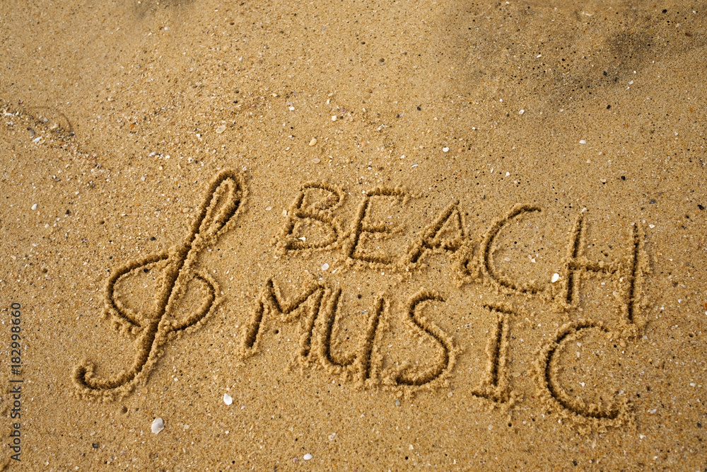 Fototapeta premium Music key and text beach music drawn on a yellow sand.