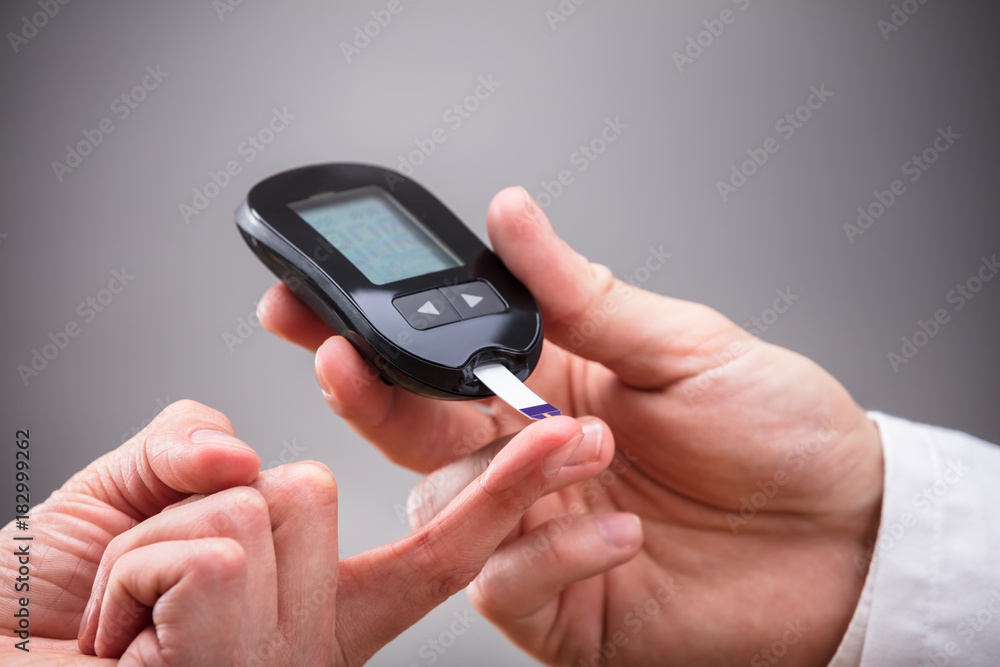 Doctor Checking Patient's Sugar Level With Glucometer Doctor Checking Patient's Sugar Level With Glucometer