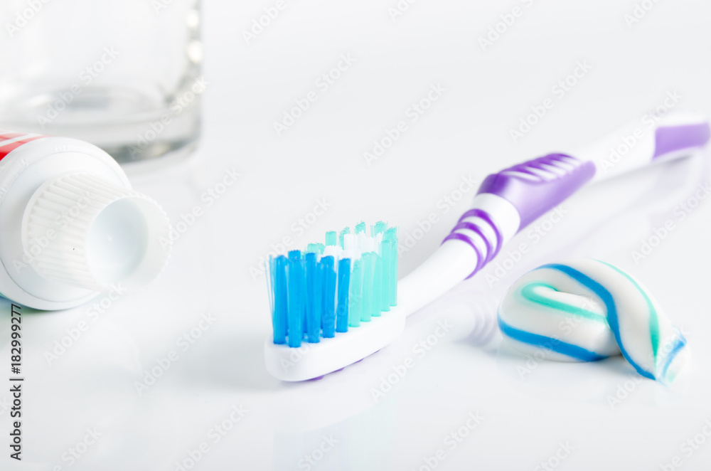 Toothbrush, tube of toothpaste and a glass in the background Toothbrush, tube of toothpaste and a glass in the background