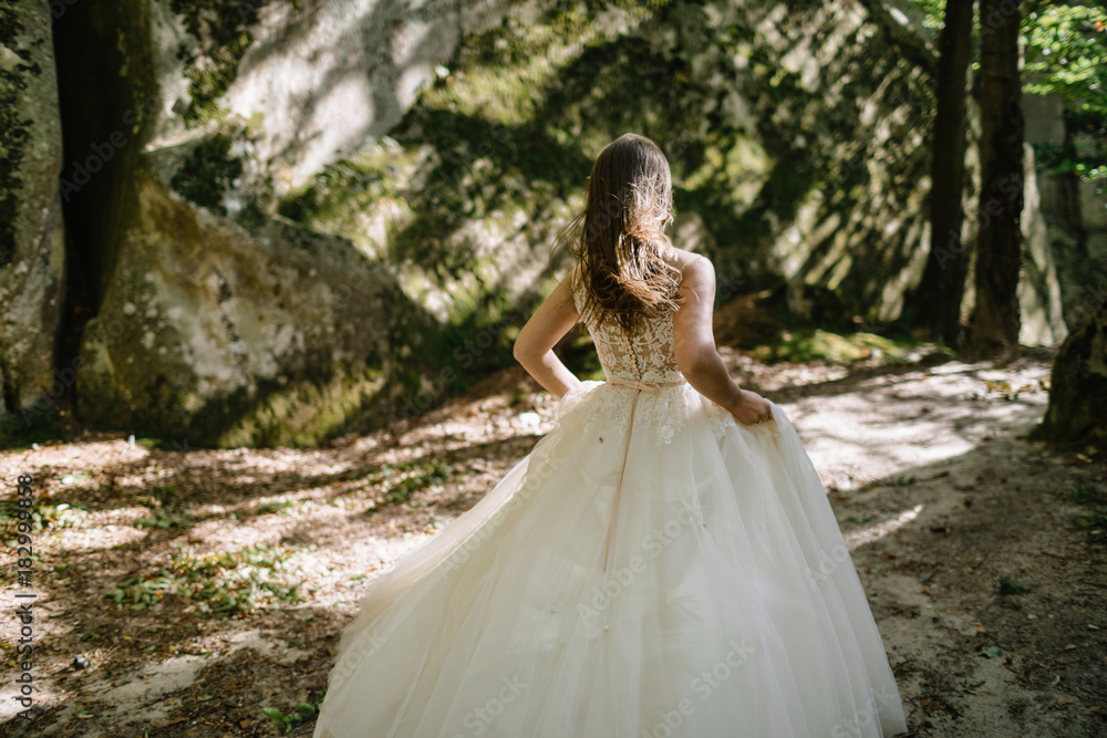 Beautiful stylish bride walking in the forest