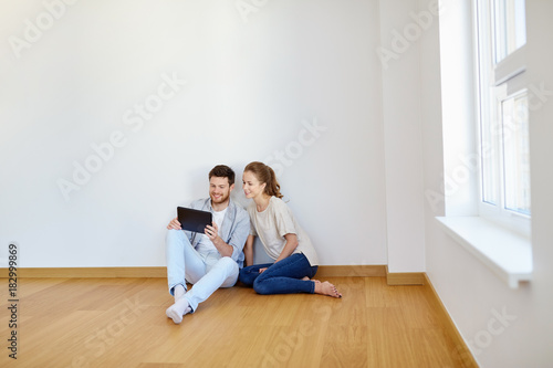 happy couple with tablet pc computer at new home