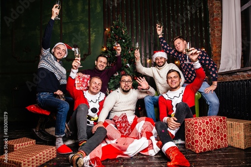 Friends celebrating Christmas with champagne glasses wish upon them sitting next to the gifts