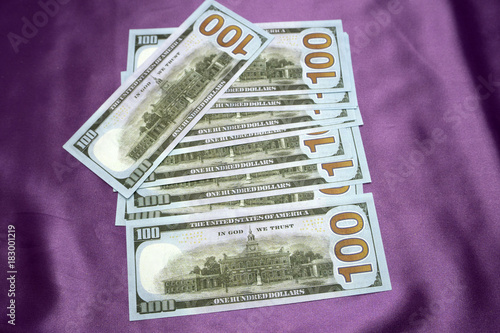 100 dollars banknotes on a purple background.