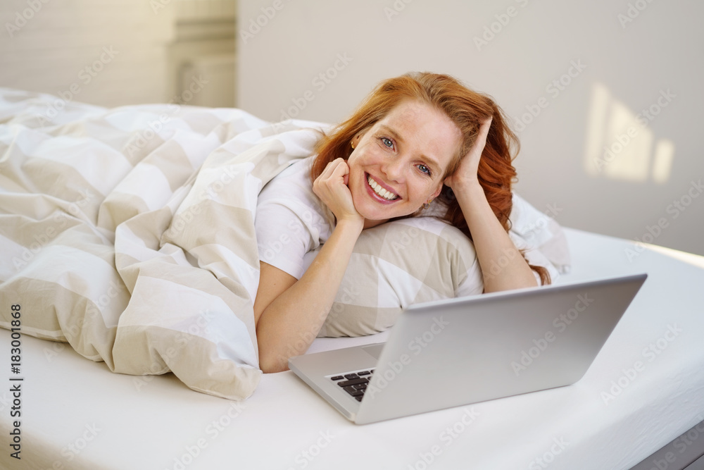 frau liegt entspannt im bett und arbeitet am laptop frau liegt entspannt im bett und arbeitet am laptop