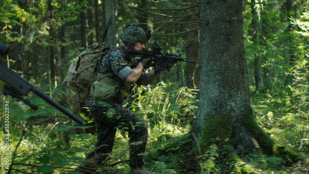 Squad of Fully Equipped Soldiers in Camouflage on a Reconnaissance Military Mission, Rifles in Firing Position. They're Running in Formation Through Dense Forest.
