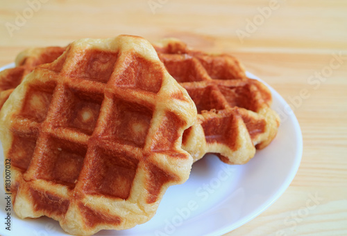 Closed up a pair of Belgian Waffle on White Plate Served on Wooden Table 
