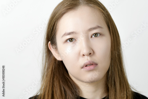 Portrait of serious Asian young woman on white background.