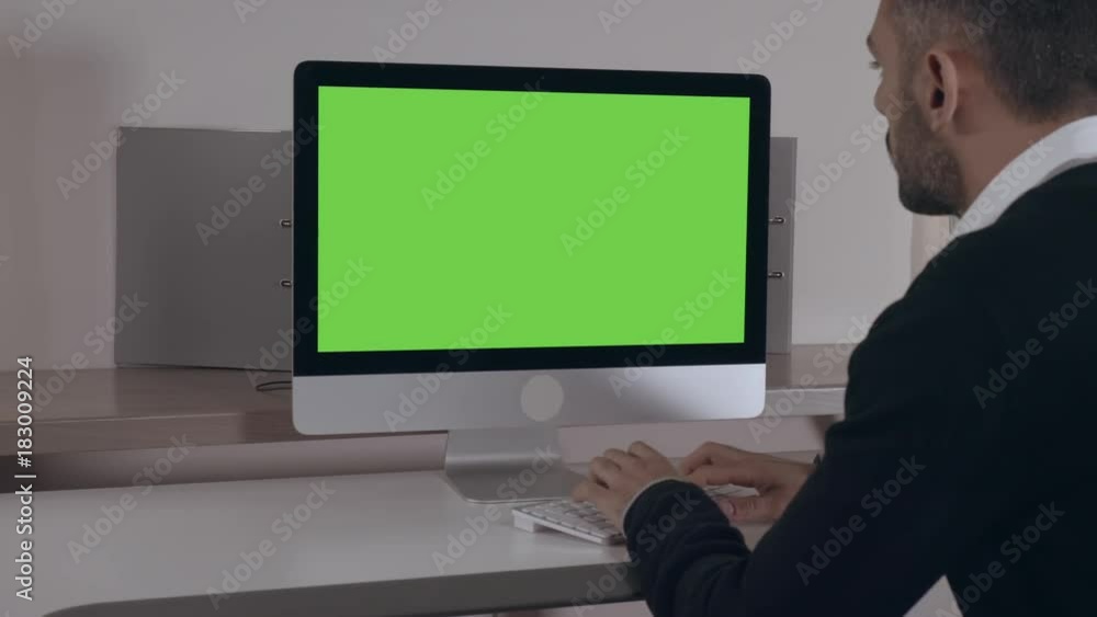adult businessman sitting at the working place at home or office typing on keyboard looking on green screen computer adult businessman sitting at the working place at home or office typing on keyboard looking on green screen computer