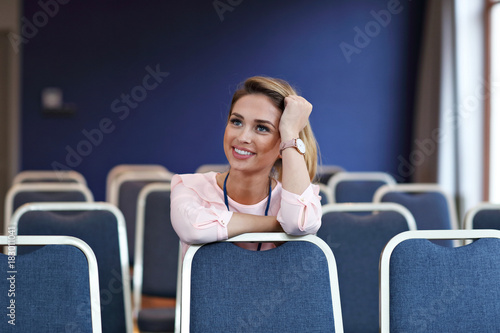 Young happy woman sitting alone in conference room