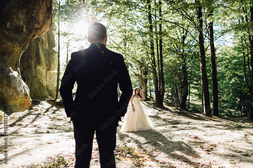 Young bride and groom walking high in mountains. Amazing weather with fog and sun Young bride and groom walking high in mountains. Amazing weather with fog and sun