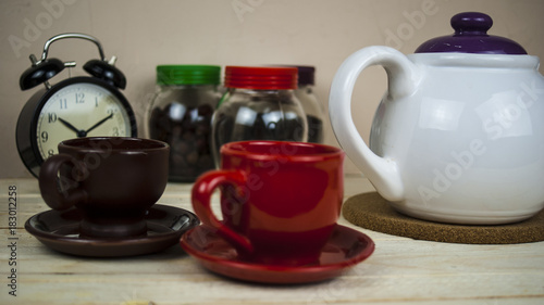 Cups with hot tea alarm clock and a kettle on the kitchen table concept morning tomorrow
