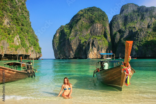 Young woman sitting on the beach at Maya Bay on Phi Phi Leh Island, Krabi Province, Thailand