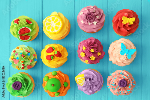 Tasty colorful cupcakes on wooden background