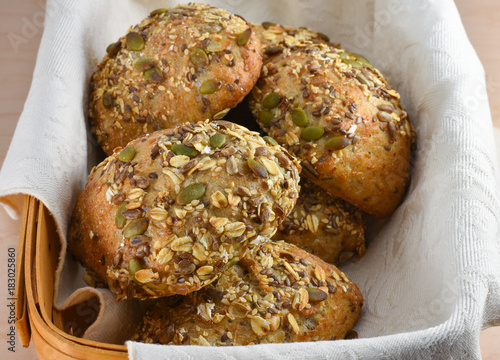 Closeup of multigrain or whole grain bread rolls in a cloth lined basket.