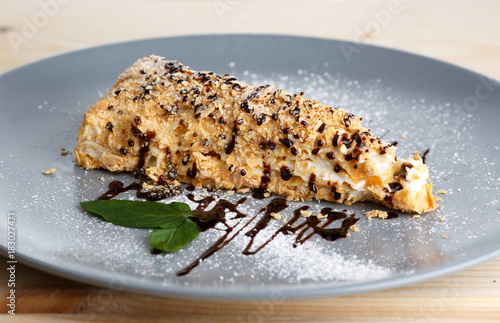 Napoleon cake with chocolate and powdered sugar in the gray plate photo