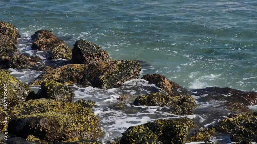 A huge wave hits the rocks. Waves hitting rocks on a tropical beach forming a splash shape. Powerful Waves on a rocky beach. A huge wave hits the rocks. Waves hitting rocks on a tropical beach forming a splash shape. Powerful Waves on a rocky beach.