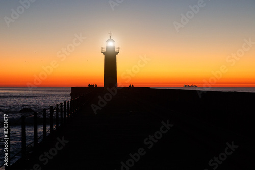 lighthouse on the ocean, silhouette at sunset. photo