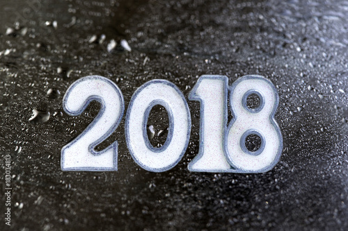 white 2018 written on a black stone or slate booard against drop of water background photo