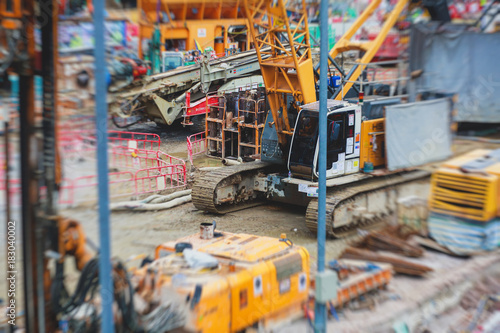 A large construction site in the city  the process of massive buliding construction with heavy vehicle at work  excavator  elevating crane and bulldozer