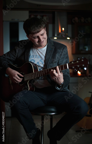 The Guitarist Guy plays the guitar in a bar in a beautiful setting on a high bar stool photo