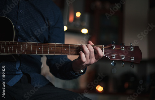 The Guitarist Guy plays the guitar in a bar in a beautiful setting on a high bar stool photo