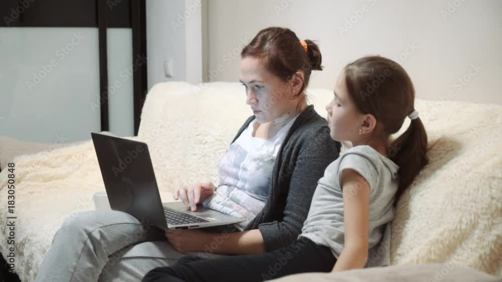 woman with daughter are sitting on sofa using laptop. woman with daughter are sitting on sofa using laptop.