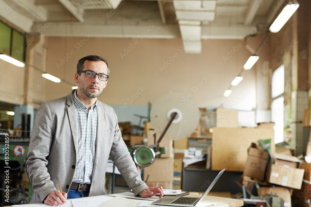Modern factory worker with laptop searching for online data by workplace Modern factory worker with laptop searching for online data by workplace