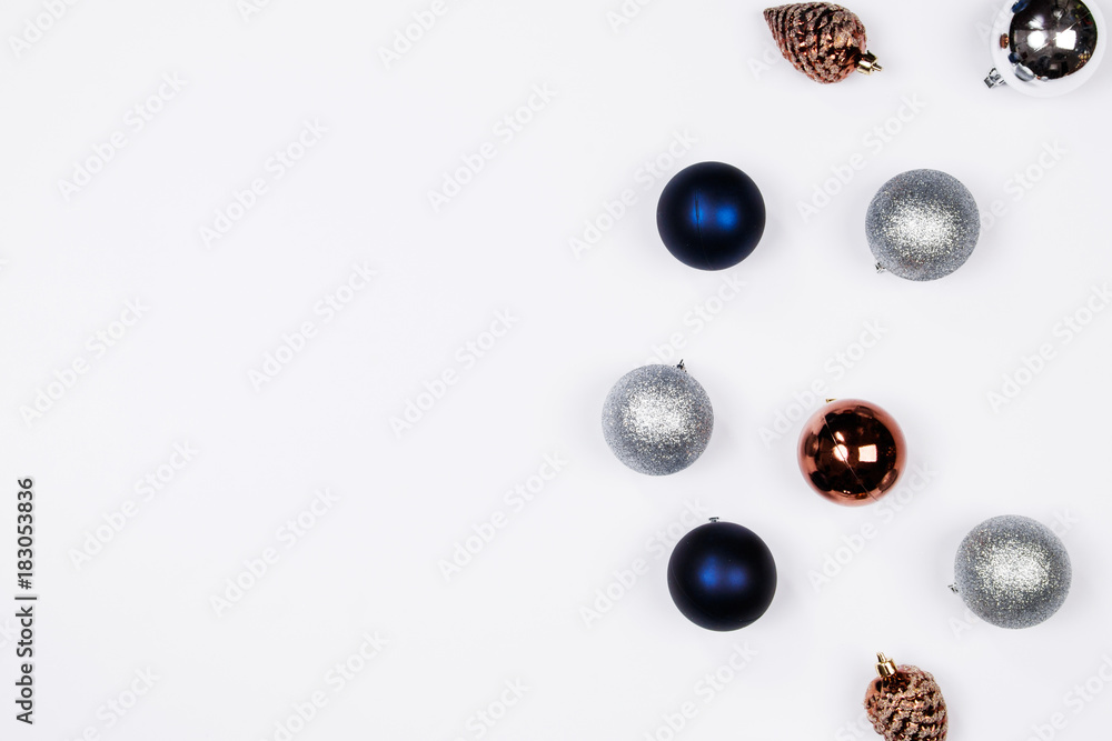 Christmas holiday background. Blue and silver glitter ball and gold pine cone christmas ornaments on a white background with copy-space. Top view. Christmas holiday background. Blue and silver glitter ball and gold pine cone christmas ornaments on a white background with copy-space. Top view.