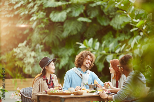 Wallpaper Mural Two guys and two girls sitting by table and having breakfast in garden room Torontodigital.ca