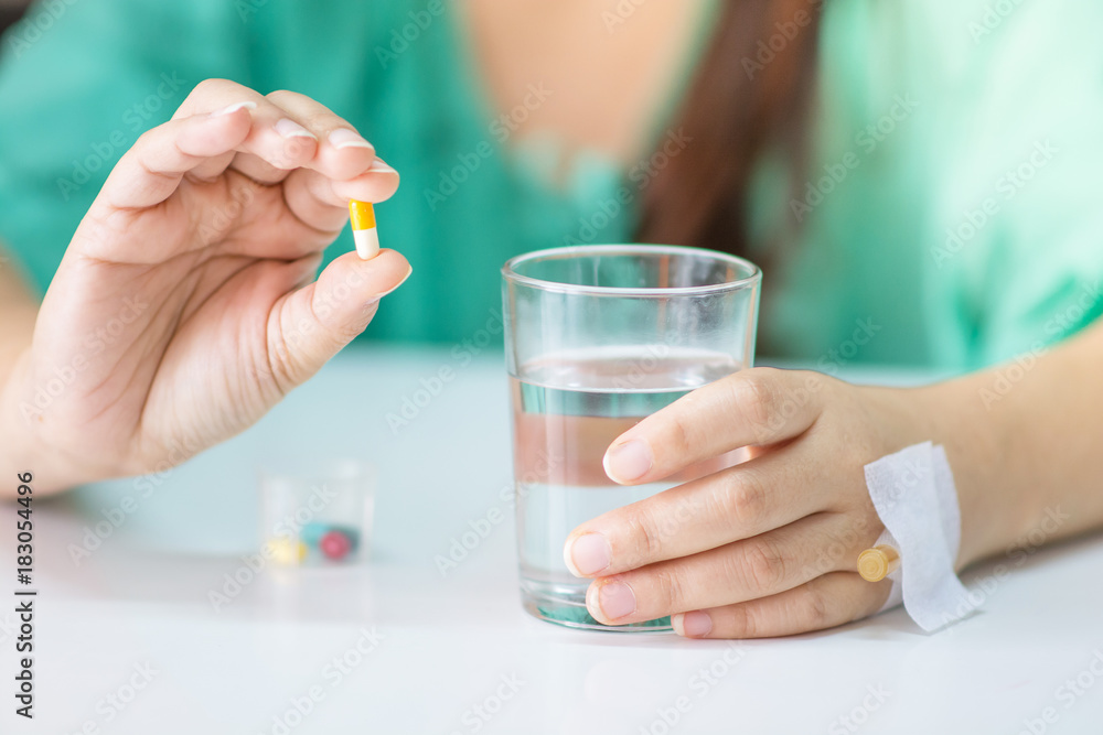 The patient handles the cup to prepare to take some medicine and a glass of water. The patient handles the cup to prepare to take some medicine and a glass of water.