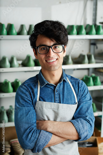 Happy young shoemaker crossing his arms on chest and looking at camera