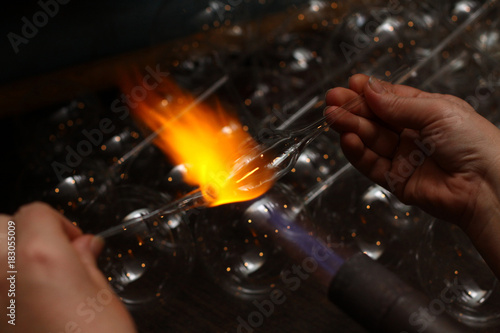 Factory of Christmas toys. The worker blows out the glass. The b