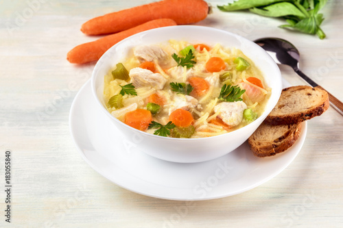 Chicken soup with noodles, bread, and copy space