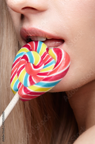 Beauty portrait of young blonde woman. Female with candy lollipop on stick in hands. photo