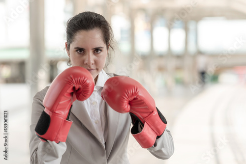 Businesswoman wearing red boxing gloves with guard posture ready to fight. © Baan Taksin Studio
