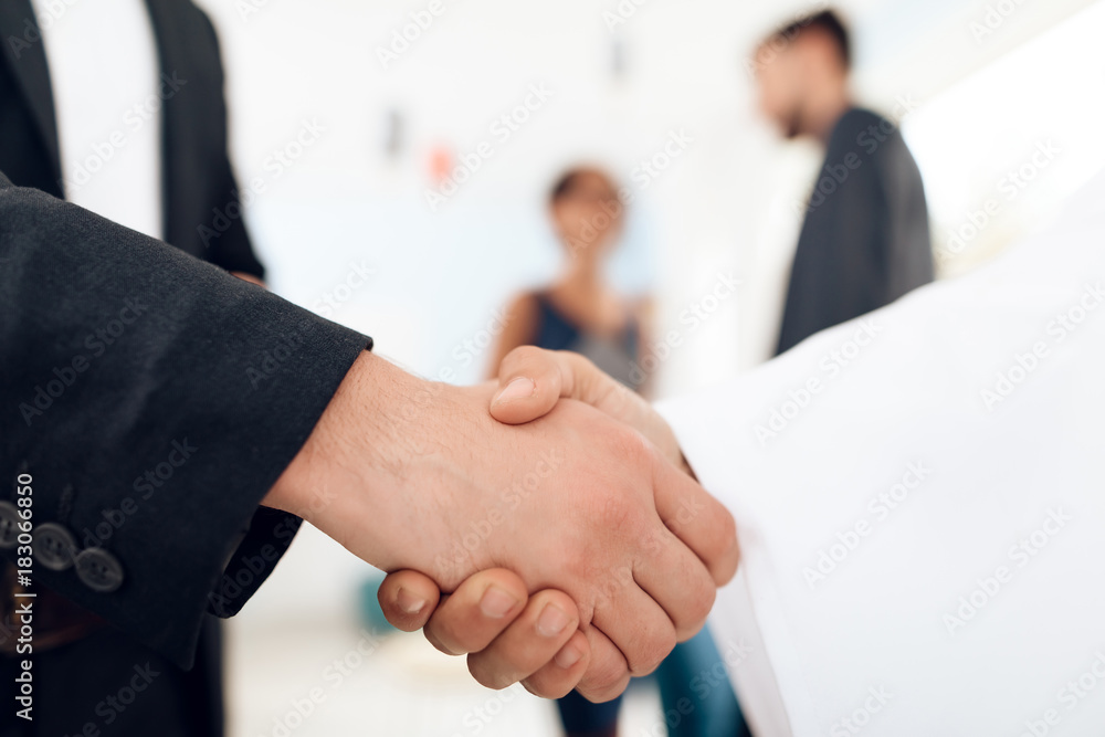 A man in arabian clothes and a man in a business suit are shaking hands.