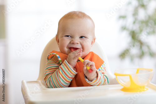 Fotografía happy baby boy waiting for food with spoon at table