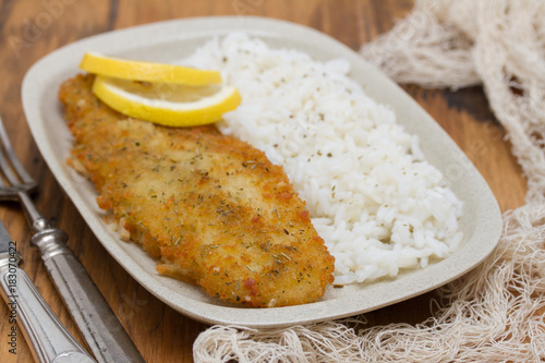 fried fish with lemon and boiled rice on dish