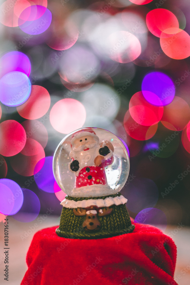 Santa glass ball decoration with Christmas lights in the background out of focus