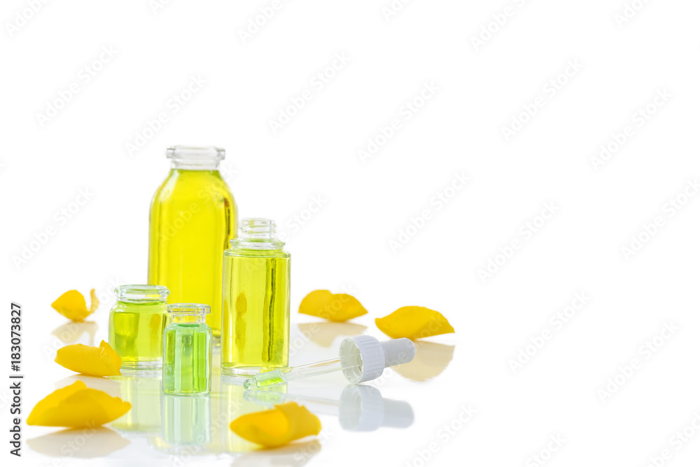 A bottle of rose essential oil with yellow roses petals on whitebackground A bottle of rose essential oil with yellow roses petals on whitebackground