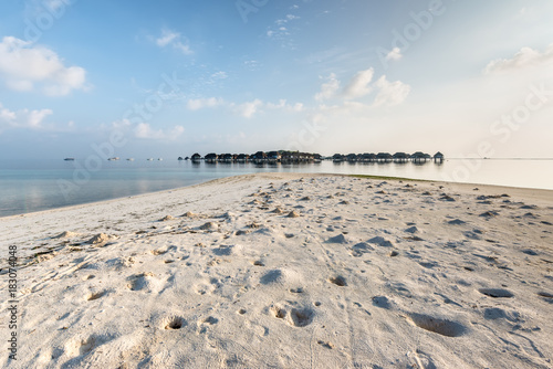 Maldives water bungalow on ocean water landscape. Crabs holes on beach sand in the foreground. photo