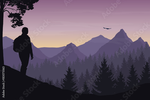 A tourist walking through a mountain landscape with a forest and watching a flying bird under a morning sky with a dawn